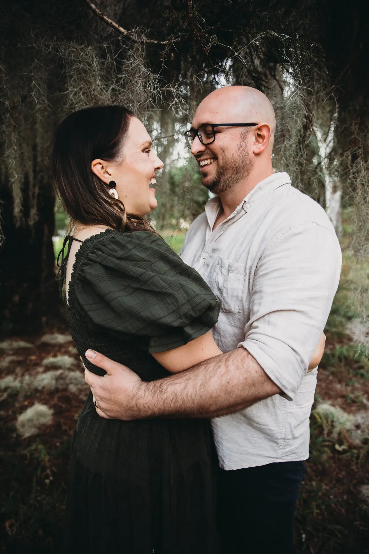 Mother and father embrace under a tree