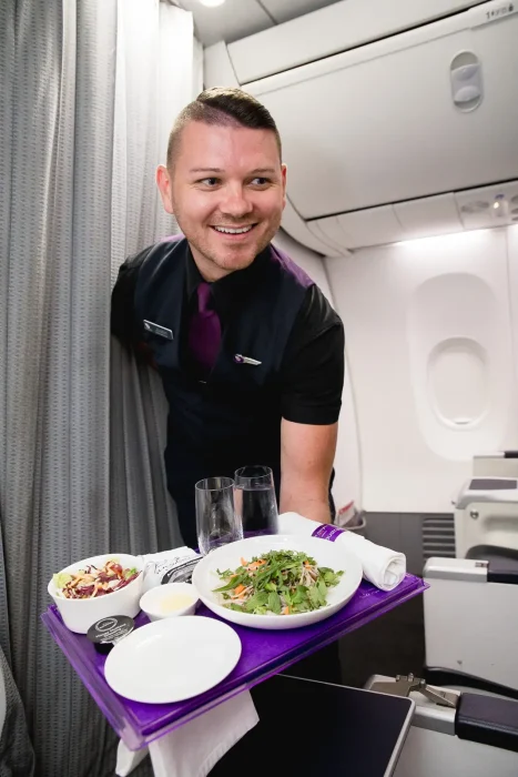 Virgin Cabin Crew member serves meal in busines class